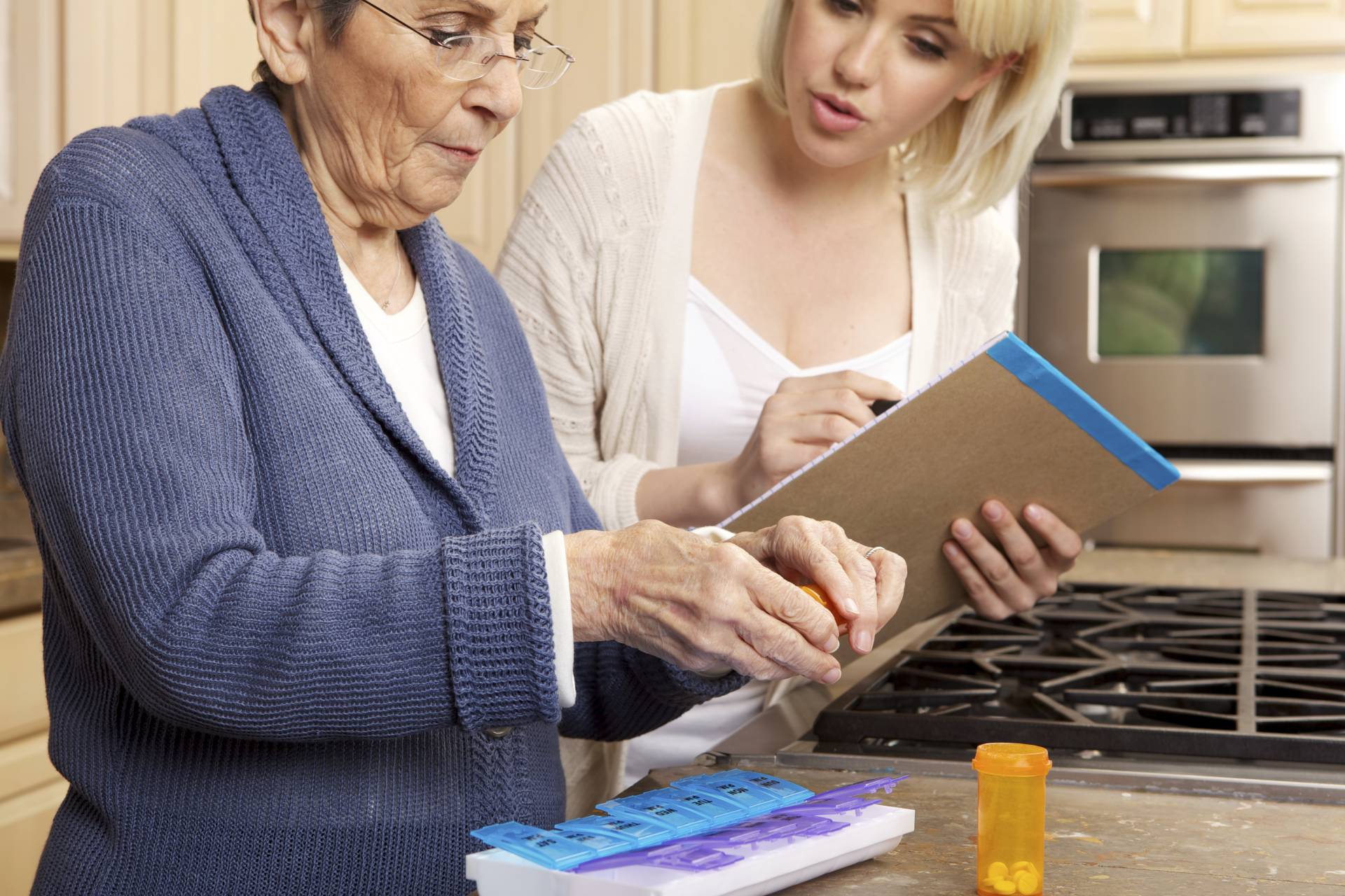Caregiver helping elderly lady take the right medication