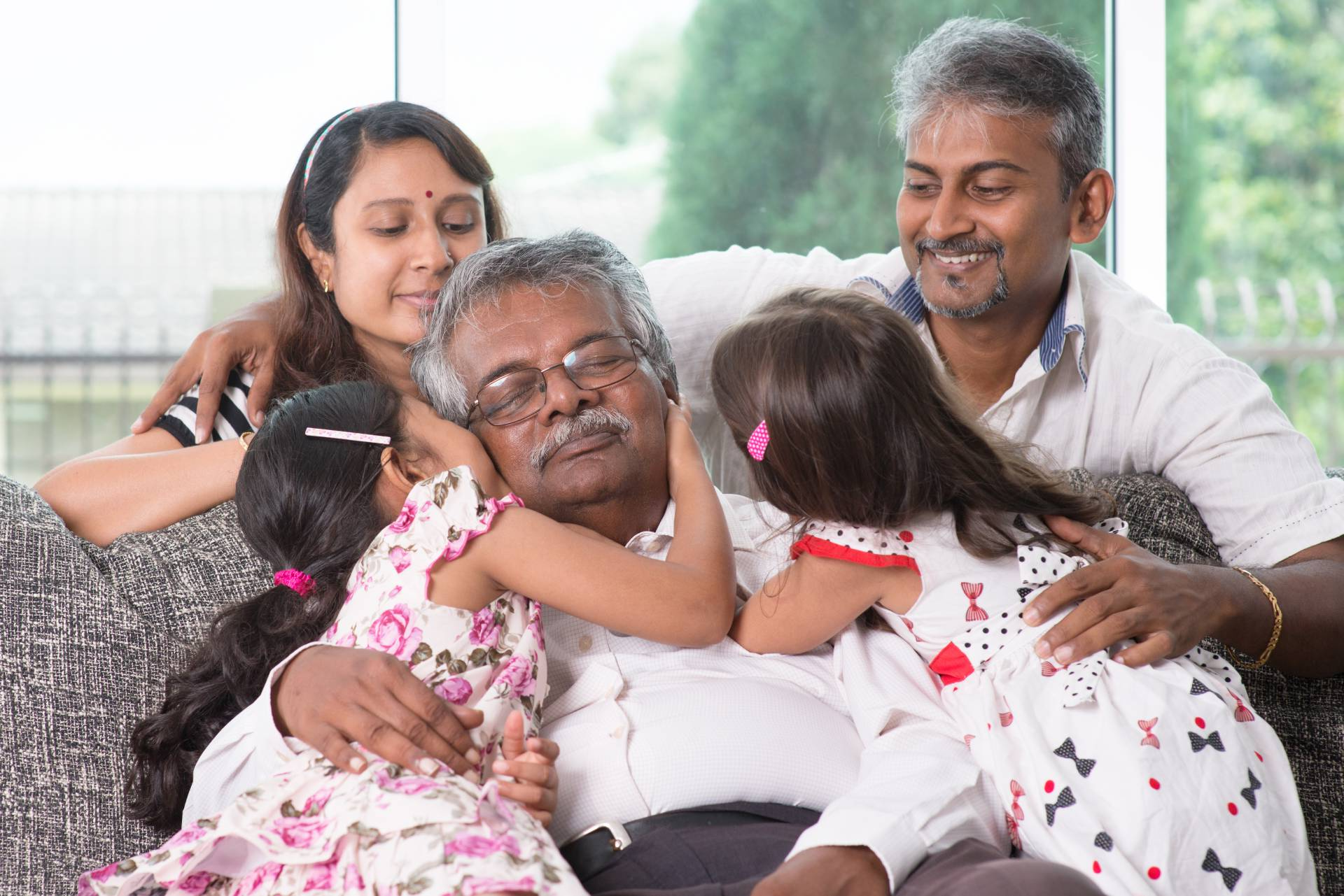 Elderly man surrounded by loved ones and hugging his family
